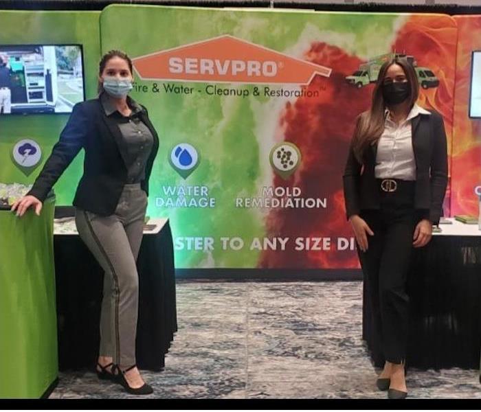 Two SERVPRO employees posing in front of a SERVPRO banner